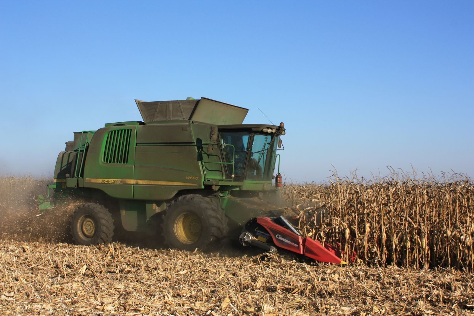 Combine harvester picking corn in a Nebraska field under a clear blue sky
